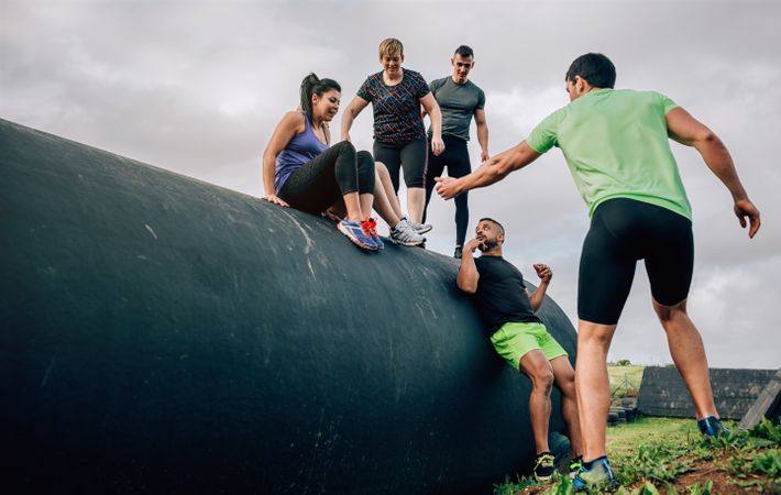 Participants in an obstacle course going down a drum