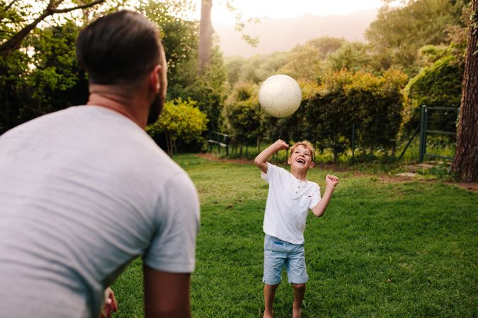 Father and son playing with a football in backyard garden