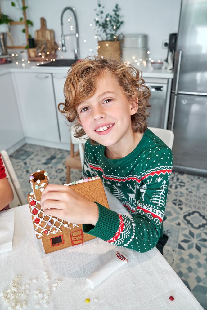 Cheerful boy making gingerbread house