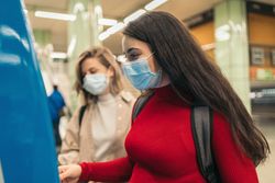 Women buying ticket for metro with mask
