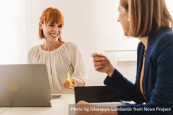 Smiling redhead woman with a nose piercing discusses work with her colleague 0KMypz
