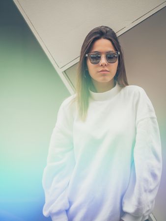 Young woman with glasses standing against wall
