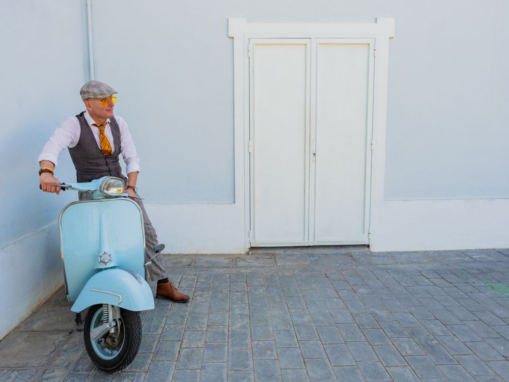Trendy man sitting on vintage scooter