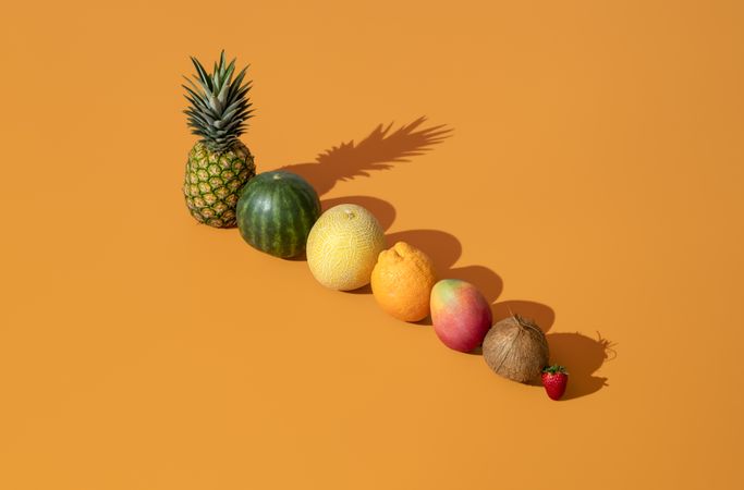 Summer fruits in bright light aligned on an orange background