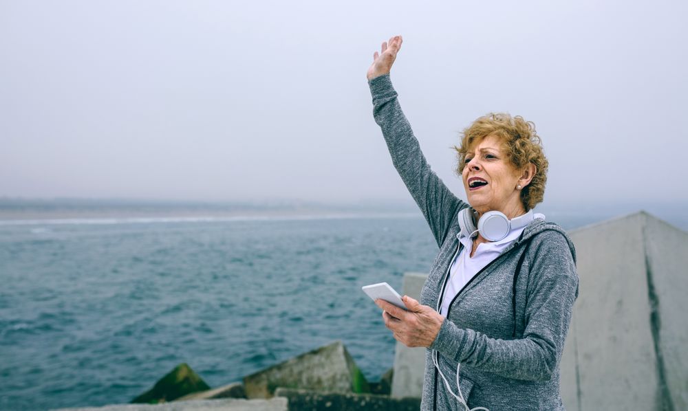 Mature sportswoman using smartphone and waving