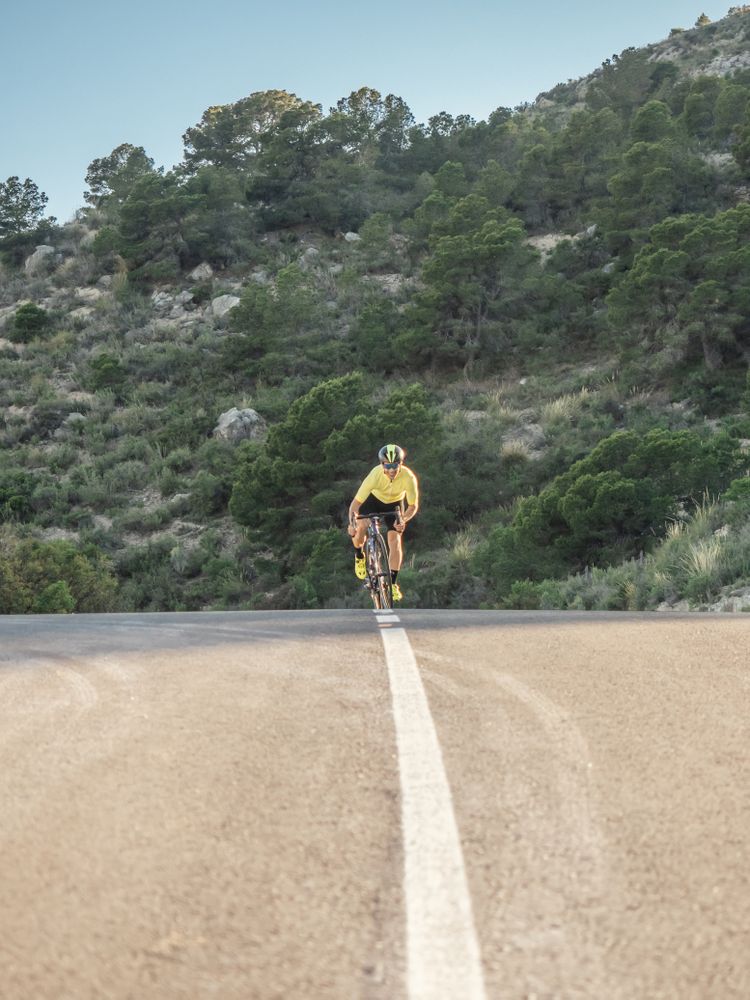 healthy man riding a bicycle on a mountain road in a sunny day