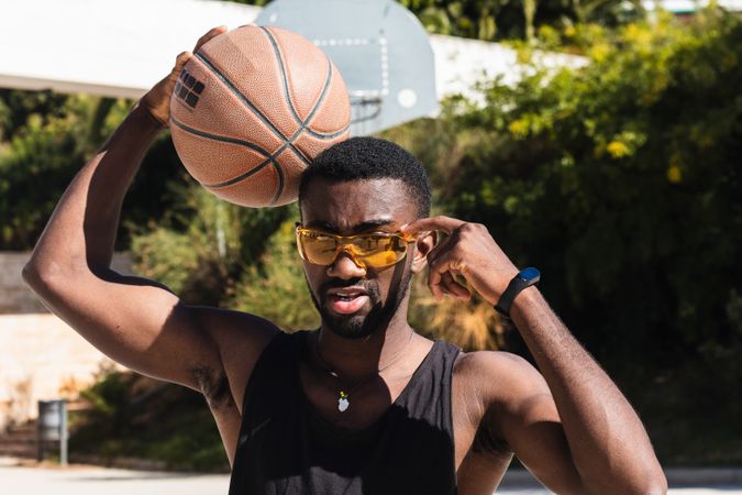 Serious Black man with basketball on sports ground