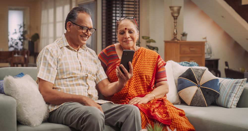 Older Couple Using Smartphone for Video Call at Home: Connecting with Family, Sharing Stories, and Celebrating Special Occasions.