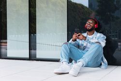 Cheerful Black man with smartphone listening to music