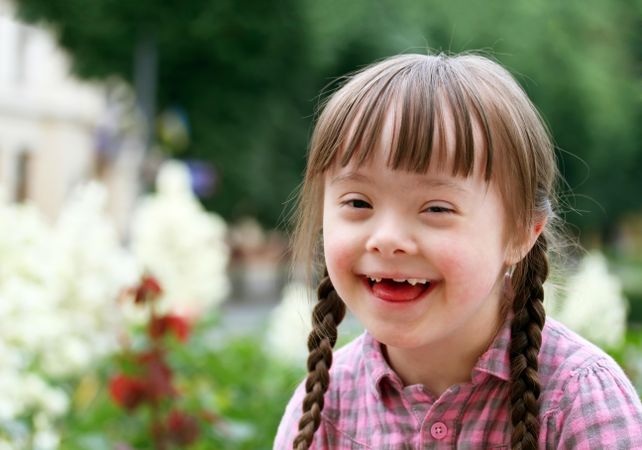 Smiling young girl with Down syndrome with her hair in braids