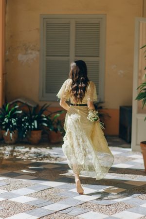Back view of woman in yellow dress walking toward a house