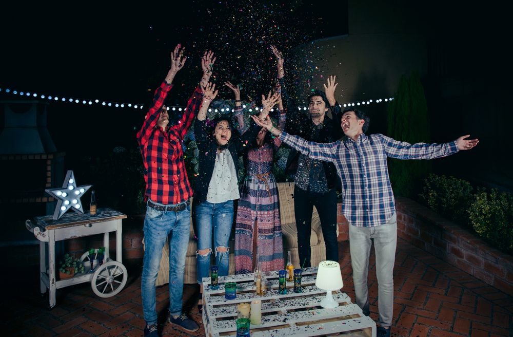 Friends celebrating at party and throwing confetti