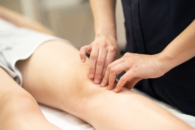 Close up of physical therapist working on female knee
