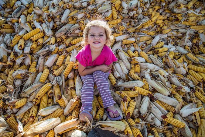Girl sitting on pile of corn on a dairy farm near Westby in Vernon County, Wisconsin