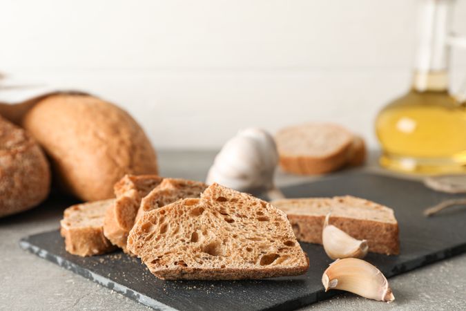 Composition with bakery products, garlic and olive oil on grey background, closeup and space for text