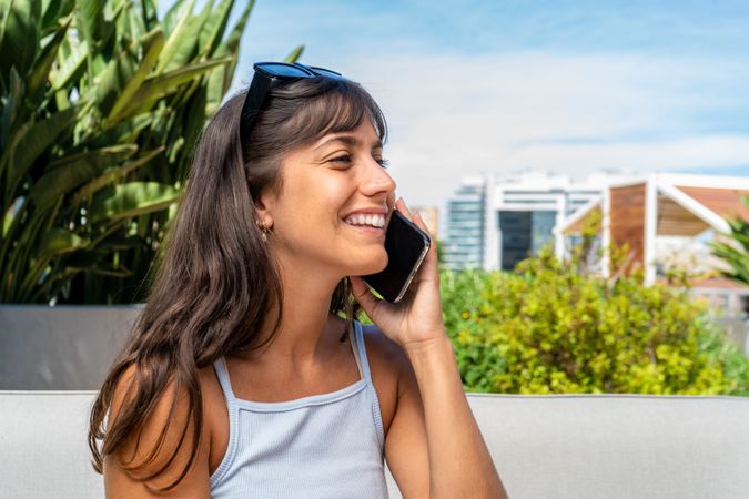 A woman is sitting on a couch and talking on her cell phone. Copy space