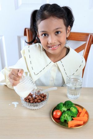 Asian Kids Pouring Milk to Chocolate Cereal