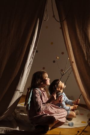 Kids sitting and playing on mat behind tent indoors