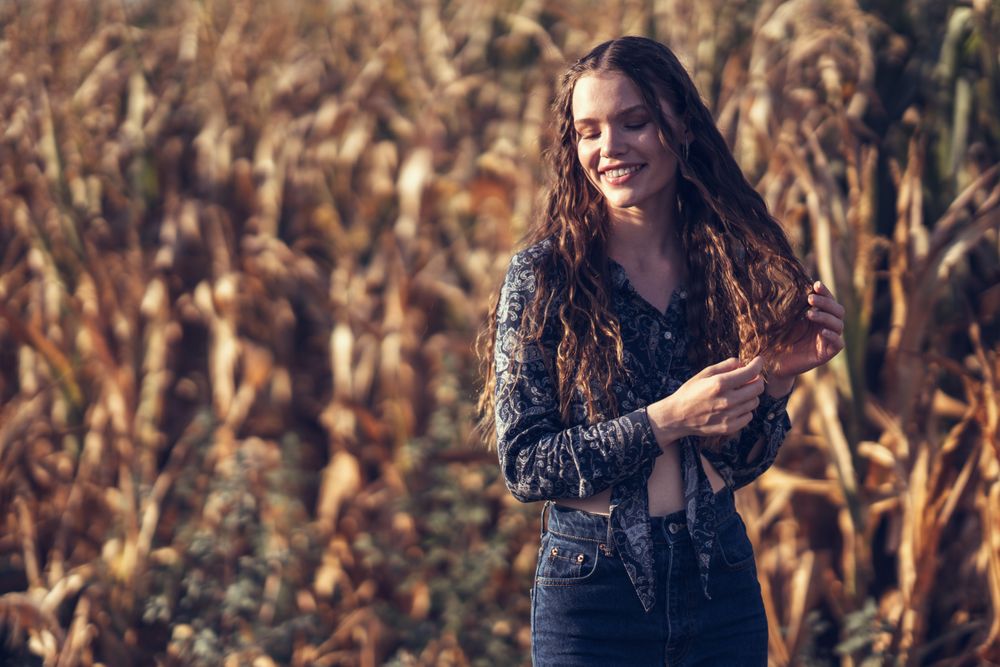 A Young Woman With a Bright Smile Enjoying the Splendor of a Beautiful Cornfield in Autumn