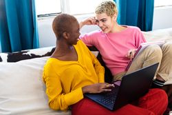 Woman with a laptop resting on couch with her partner at home