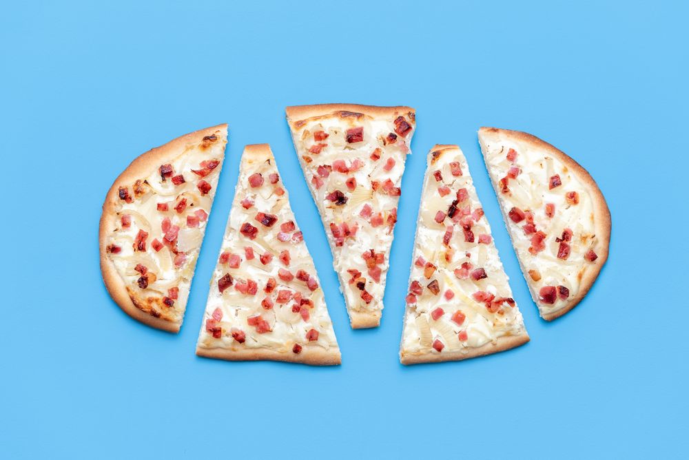 Sliced Tarte flambee above view, isolated on a blue background