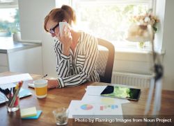 Busy woman in striped shirt taking phone call at her desk 0PQee5