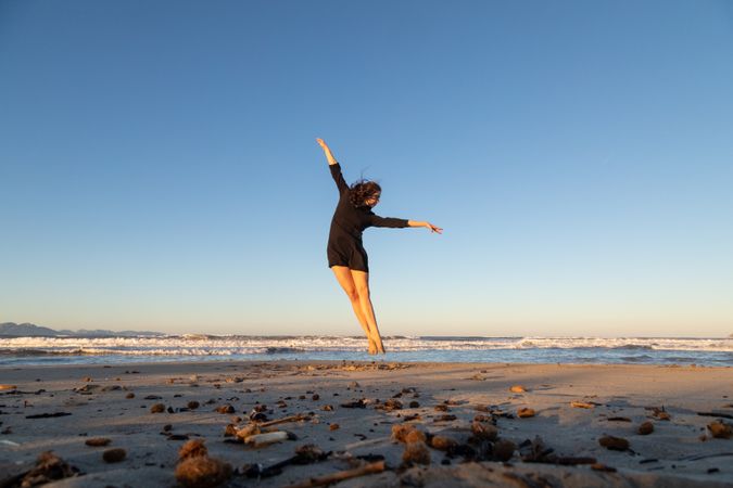 Young woman dancing and posing near water on shore