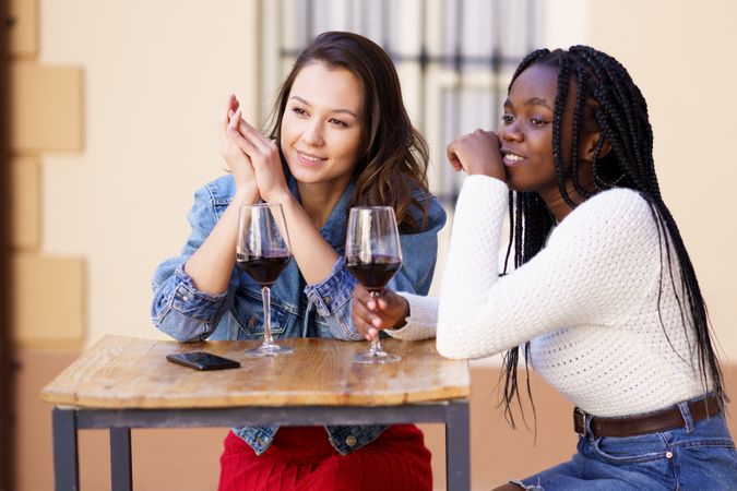 Female friends looking off in the distance at a restaurant with red wine