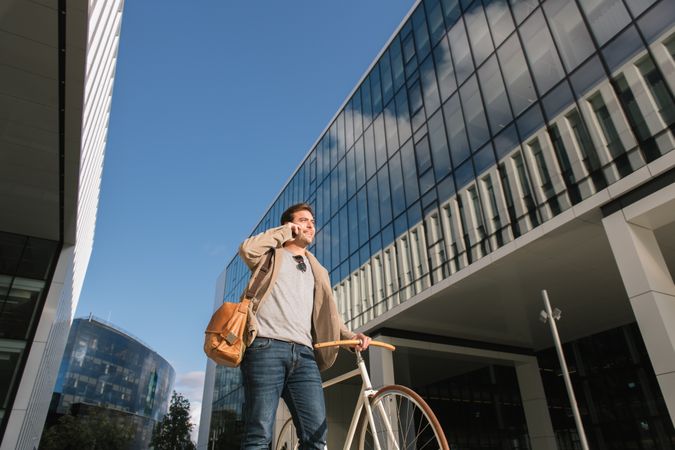 Man phoning while standing against modern building in downtown