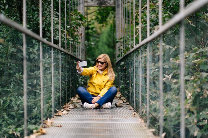 Happy female traveler taking selfie on suspension bridge in summer