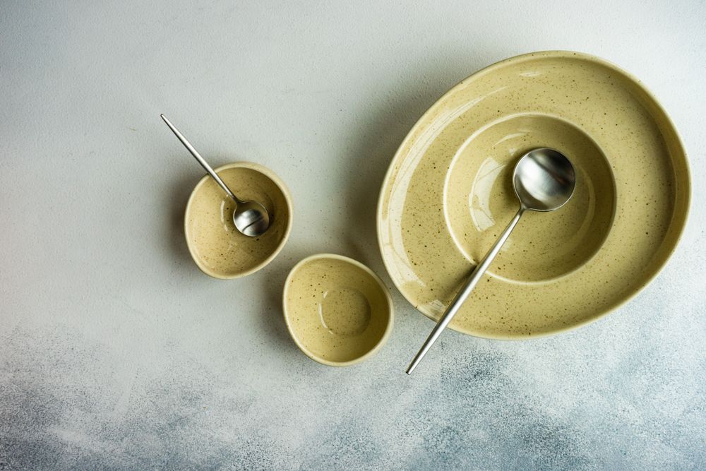 Rustic table setting with three yellow bowls and spoons