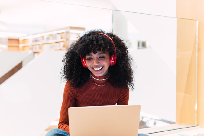 Glad female listening to music from laptop