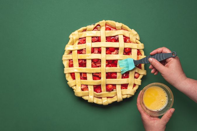 Brushing strawberry and rhubarb pie with eggwash
