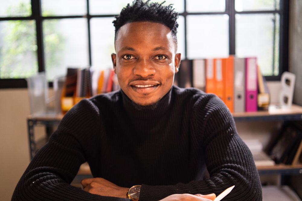 Black male creative smiling and sitting in relaxed modern office