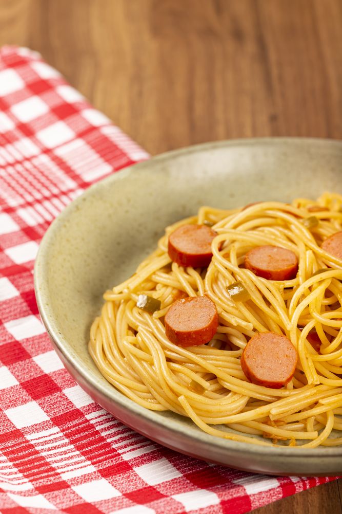 spaghetti pasta with sliced sausages and tomato sauce.