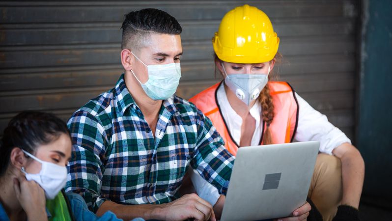 Construction workers reading plans on laptop together