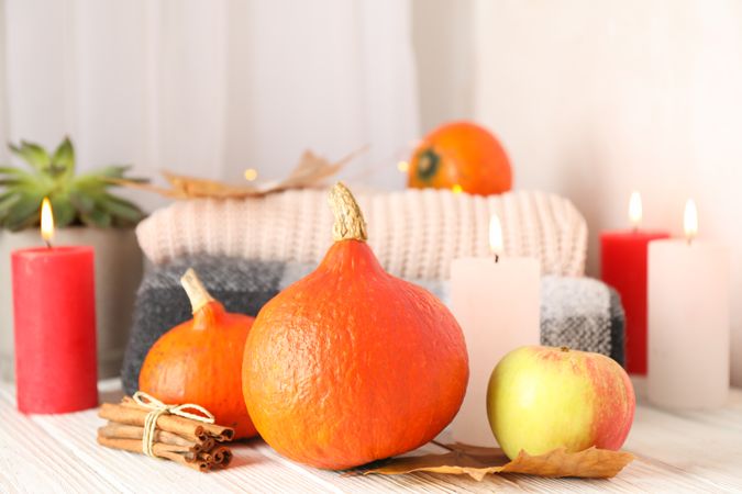 Pumpkins, clothes, leaves and candles on wooden background, copy space