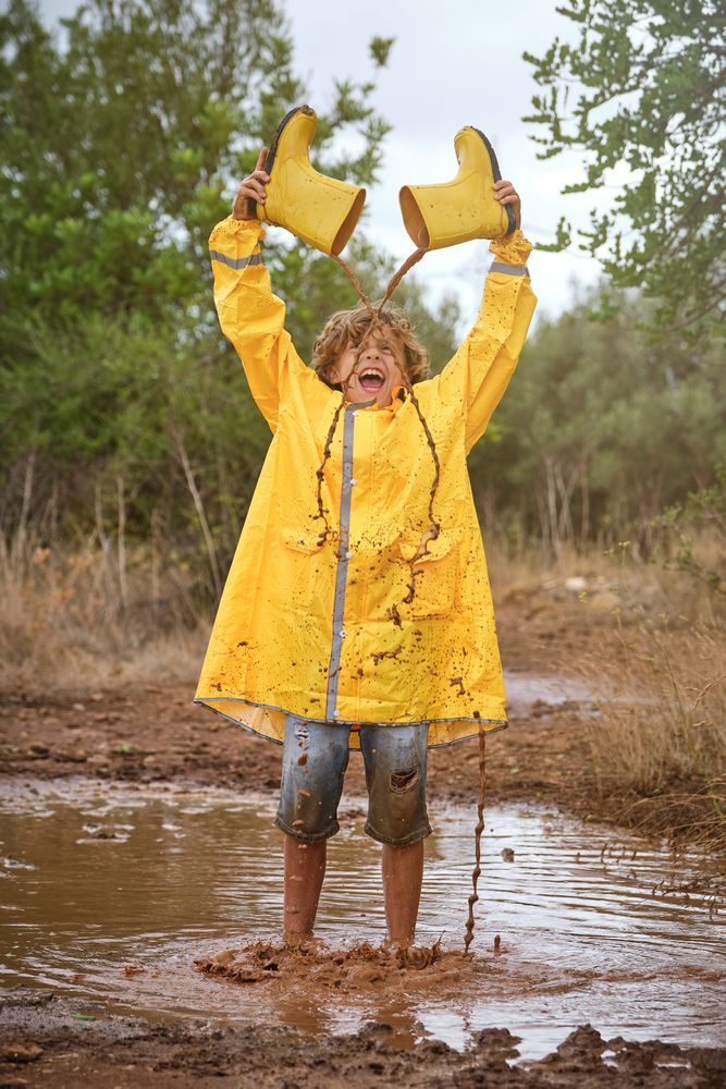 Excited boy playing in puddle in nature