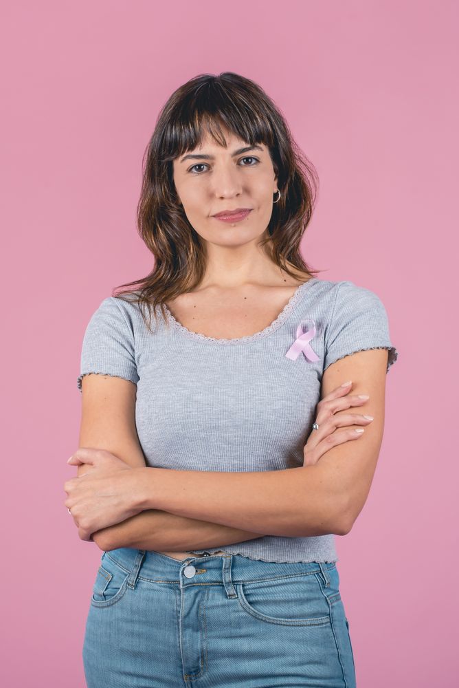 Serious woman wearing pink breast cancer awareness ribbon. Vertical shot.