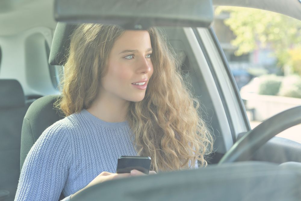 Woman using smartphone in car