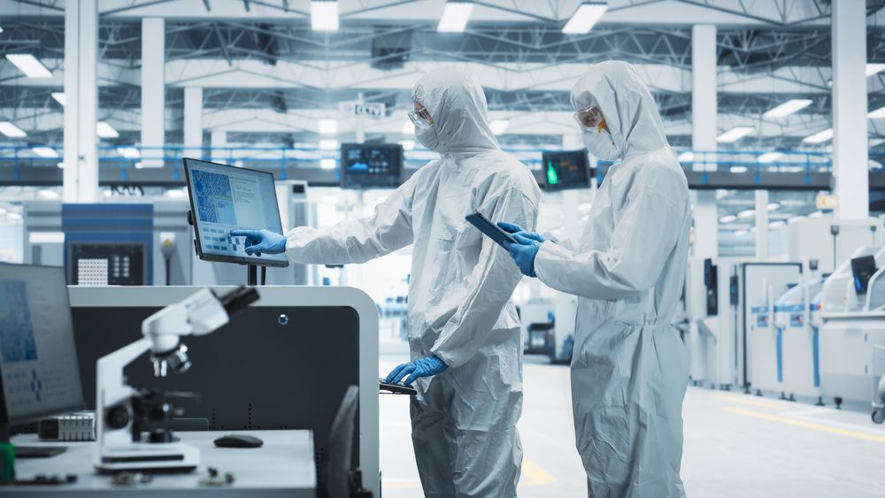 Side view of two people working in hazmat suits at register