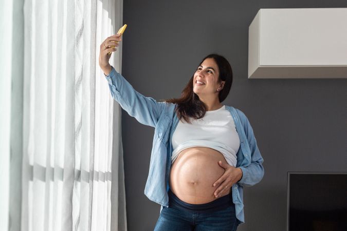 Pregnant woman taking selfie at home