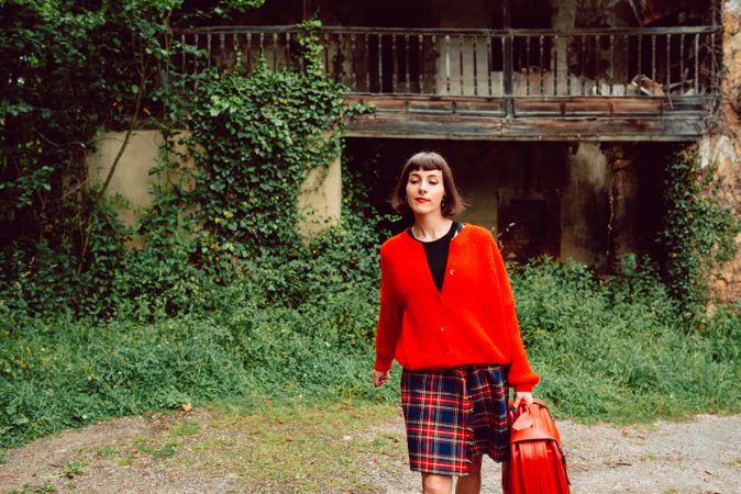 Woman in red with big red suitcase in forest