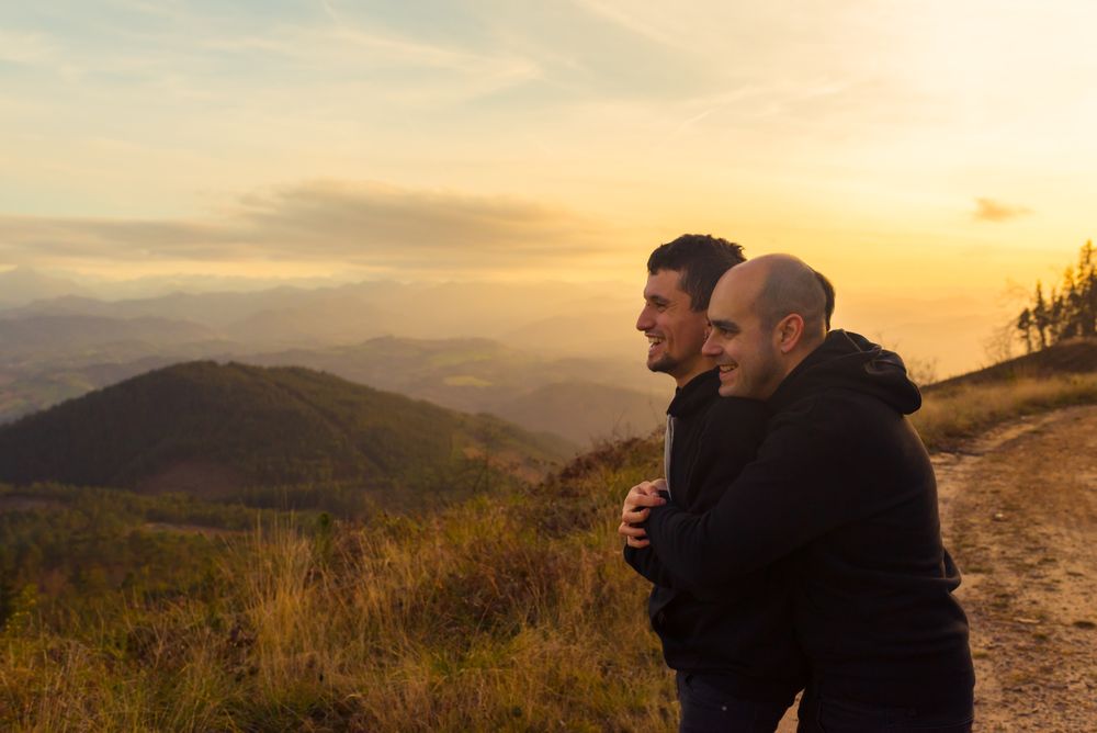 Men hugging on road on hill