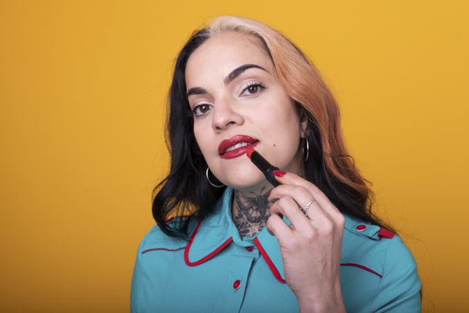 woman applying a bright red color lipstick on her lips