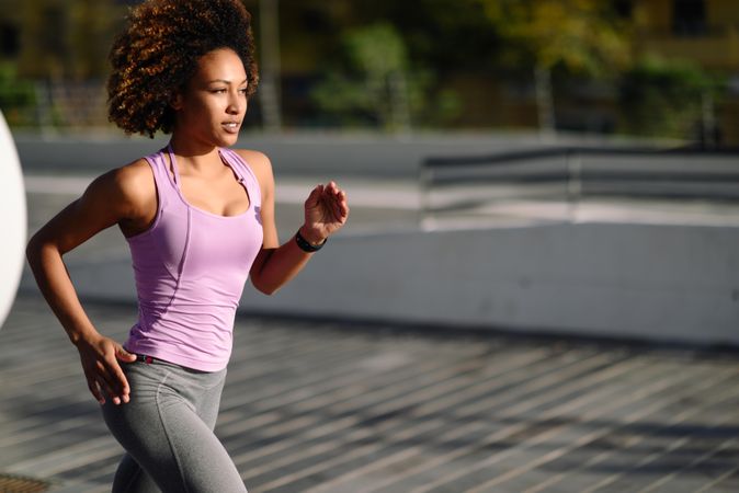 Woman with afro hairstyle running outside in sports wear