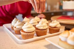 Crop confectioner making cupcakes in kitchen