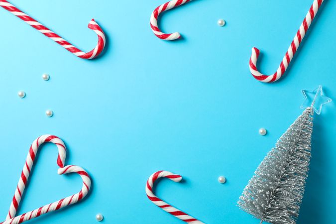 Composition with sweet candy canes on color background, space for text