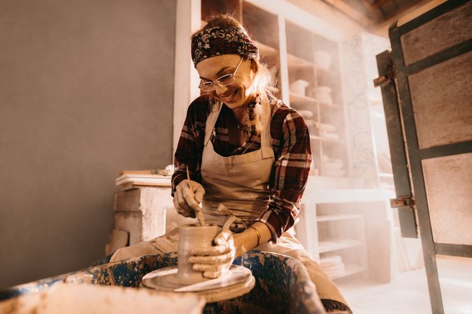 Happy female potter making clay pot