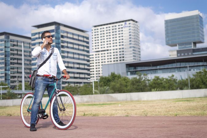 Male with colorful bicycle talking on phone on city bike path